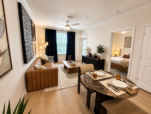 A dining room with a table set for two and a couch.