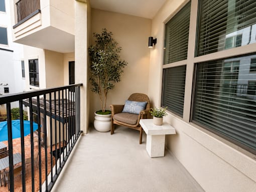 A balcony with a chair, table, and potted plant.