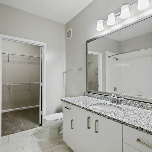 A bathroom with a marble countertop and a large mirror.