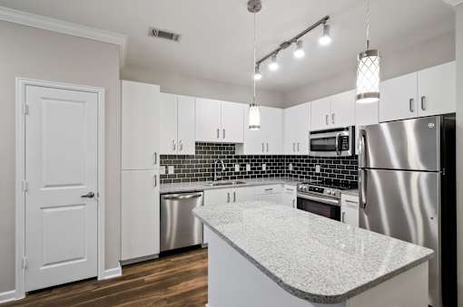 A kitchen with a white counter top and stainless steel appliances.