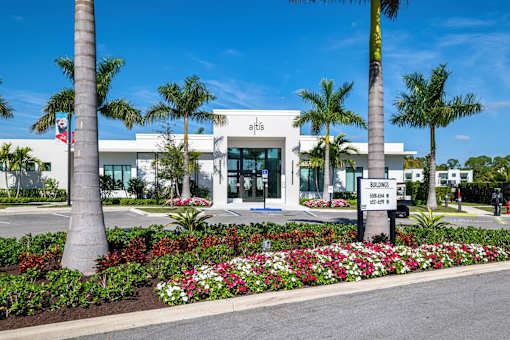 A white building with palm trees in front.