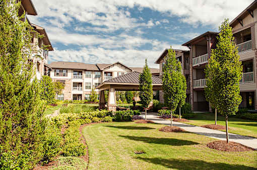 A row of apartment buildings with a well-manicured lawn in front.