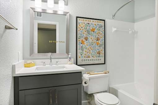 A bathroom with a toilet, sink, and poster.