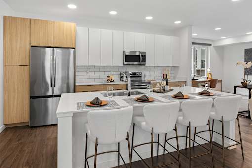 A modern kitchen with white chairs and a wooden cabinet.