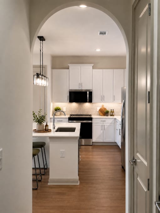 A kitchen with white cabinets and a wooden floor.