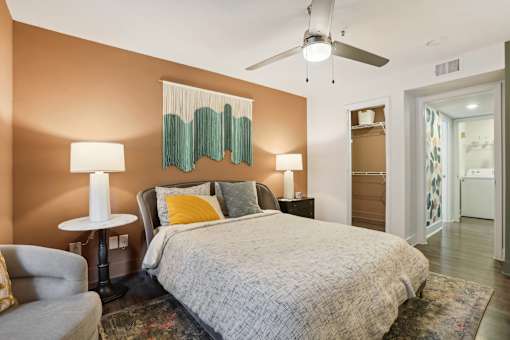 Atlanta, GA, Apartments with In-Unit Washer and Dryer - Virginia Highlands - Bedroom with Hardwood Floor, Area Rug, Bed, Nightstands with Lamps, Armchar, Ceiling Fan, and Spacious Closet.
