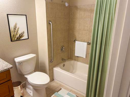 A bathroom with a toilet, a bathtub, and a picture on the wall.