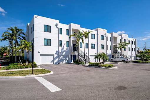 A white building with a car parked in front.