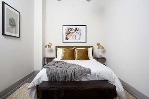 A bedroom with a bed, nightstands, and a painting on the wall.