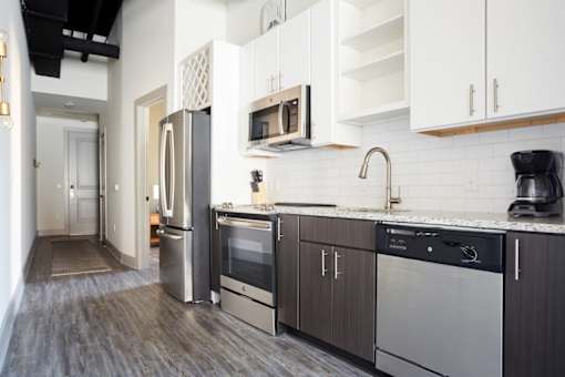 A kitchen with a refrigerator, oven, and sink.