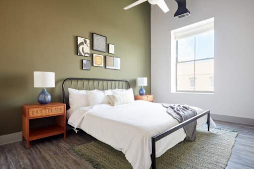 A bedroom with a bed, nightstand, and pictures on the wall.