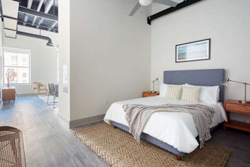 A bedroom with a bed, a chair, and a ceiling fan.