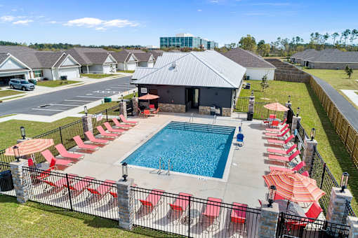 an aerial view of a swimming pool with red chairs and umbrellas