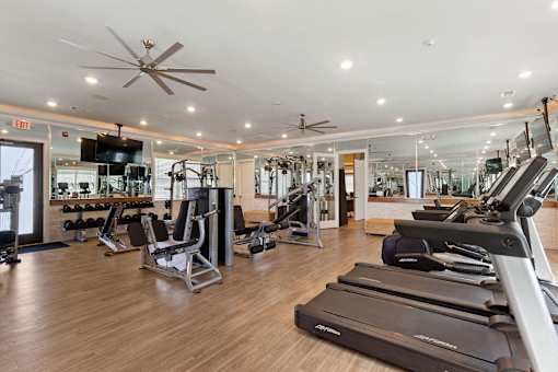 a gym with cardio machines and weights on a wooden floor