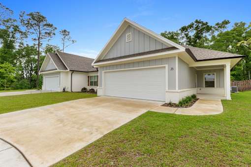 a white and gray house with a driveway and a lawn