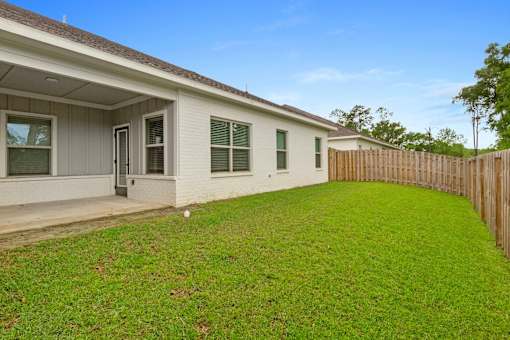 the backyard of a house with a green lawn and a wooden fence
