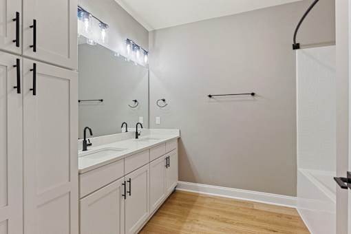 a bathroom with two sinks and a shower and white cabinets