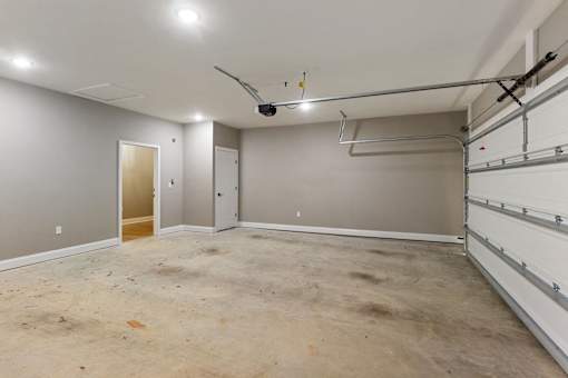an empty basement with a garage door and a ceiling fan