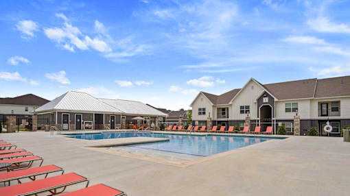 A swimming pool surrounded by red sun loungers and a building in the background.