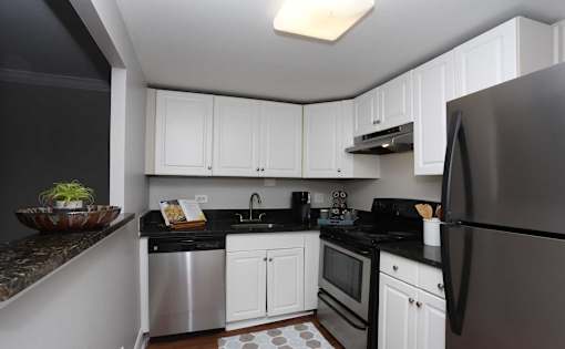 A kitchen with black countertops and white cabinets.