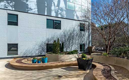 A modern building with a circular garden in front.