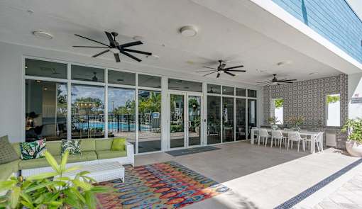 A patio with a white couch and a colorful rug.