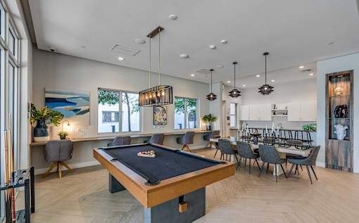 A pool table is in the middle of a room with a bar and a dining table.