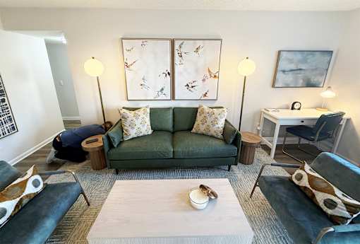 A living room with a green couch and a white coffee table.