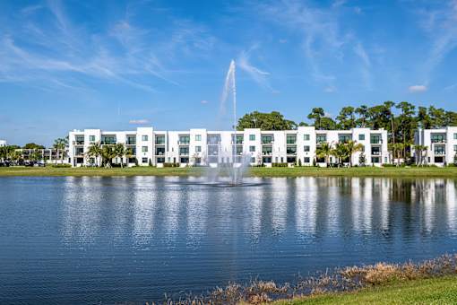 A white building with a fountain in front of it.