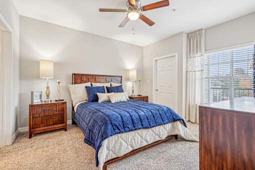 A bedroom with a bed, nightstand, and window.