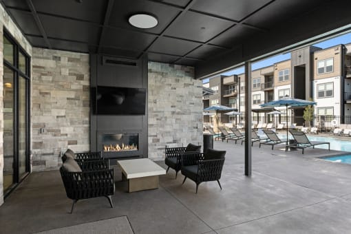 a patio with chairs and a fireplace and a pool with umbrellas