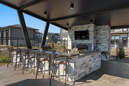 a covered patio with a stone fireplace and bar