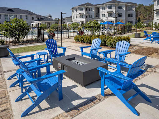 A person is sitting on a blue chair in a courtyard with a fire pit.