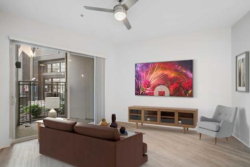 A living room with a brown couch, a grey armchair, a wooden cabinet, and a painting on the wall.