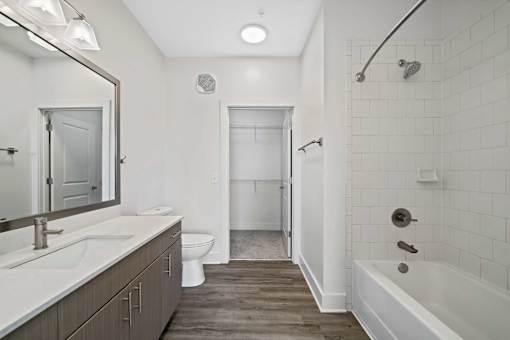 A white bathroom with a wooden floor and a white tub.