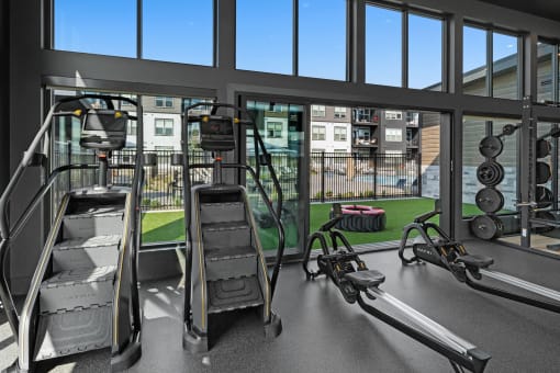 a gym with weights and cardio equipment and a view of a building