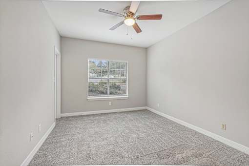 A room with a ceiling fan and carpeted floor.