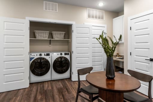 a washer and dryer in a laundry room with a table and chairs