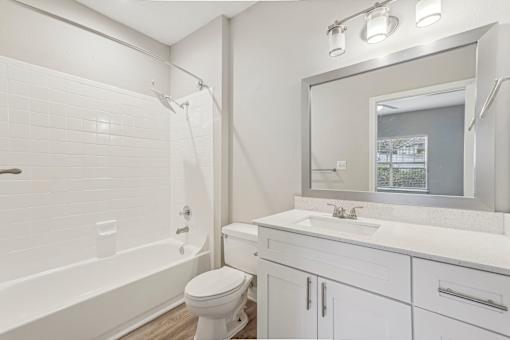 A white bathroom with a toilet, sink, and mirror.
