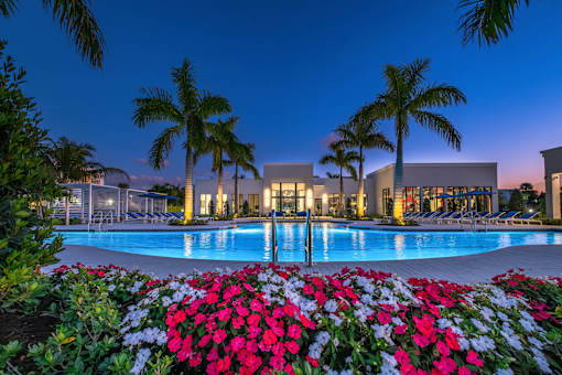 A pool surrounded by red flowers at dusk.