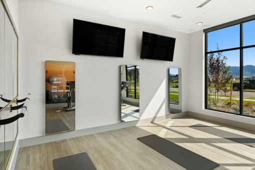 a yoga room with two monitors on the wall and yoga mats on the floor