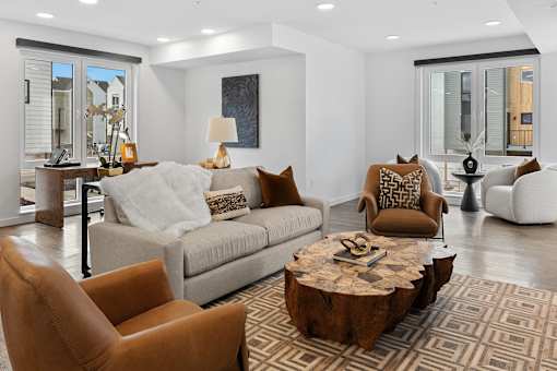 Bozeman, MT, Townhomes with attached Garage - Highmark Bozeman - Furnished Resident Lounge With Sofa Seating, Leather Accent Chairs, Large Windows, Modern Lighting, And Wood Coffee Table.