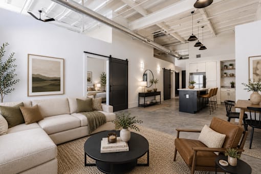 A living room with a white couch, a black coffee table, and a brown leather chair.