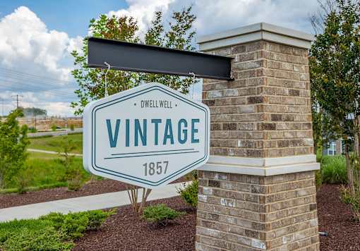 A sign that says Vintage 1857 is mounted on a brick pillar.
