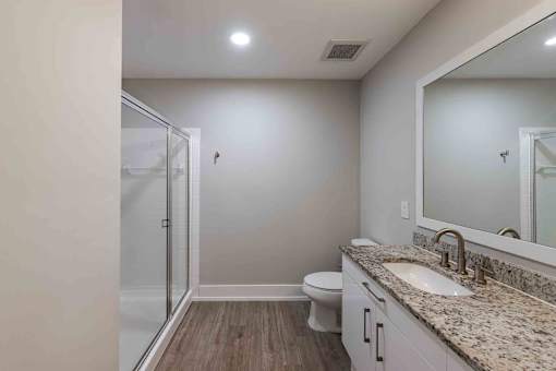 A bathroom with a sink, toilet, and mirror.