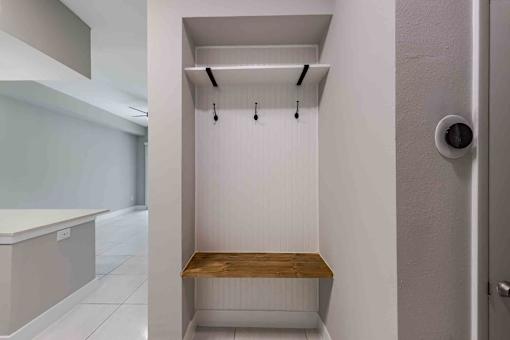 A small white bathroom with a wooden bench.
