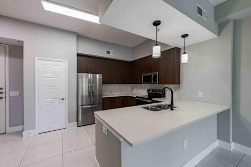 A kitchen with a white countertop and a stainless steel refrigerator.