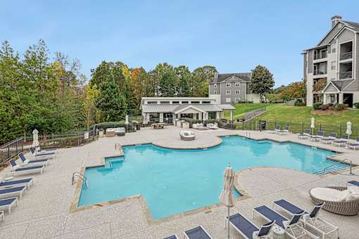 A large swimming pool surrounded by lounge chairs and umbrellas.