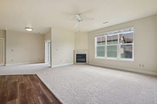 A spacious living room with a fireplace and a ceiling fan.