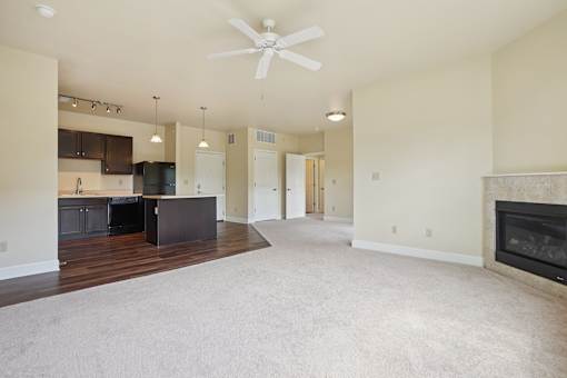 A spacious living room with a fireplace and a ceiling fan.